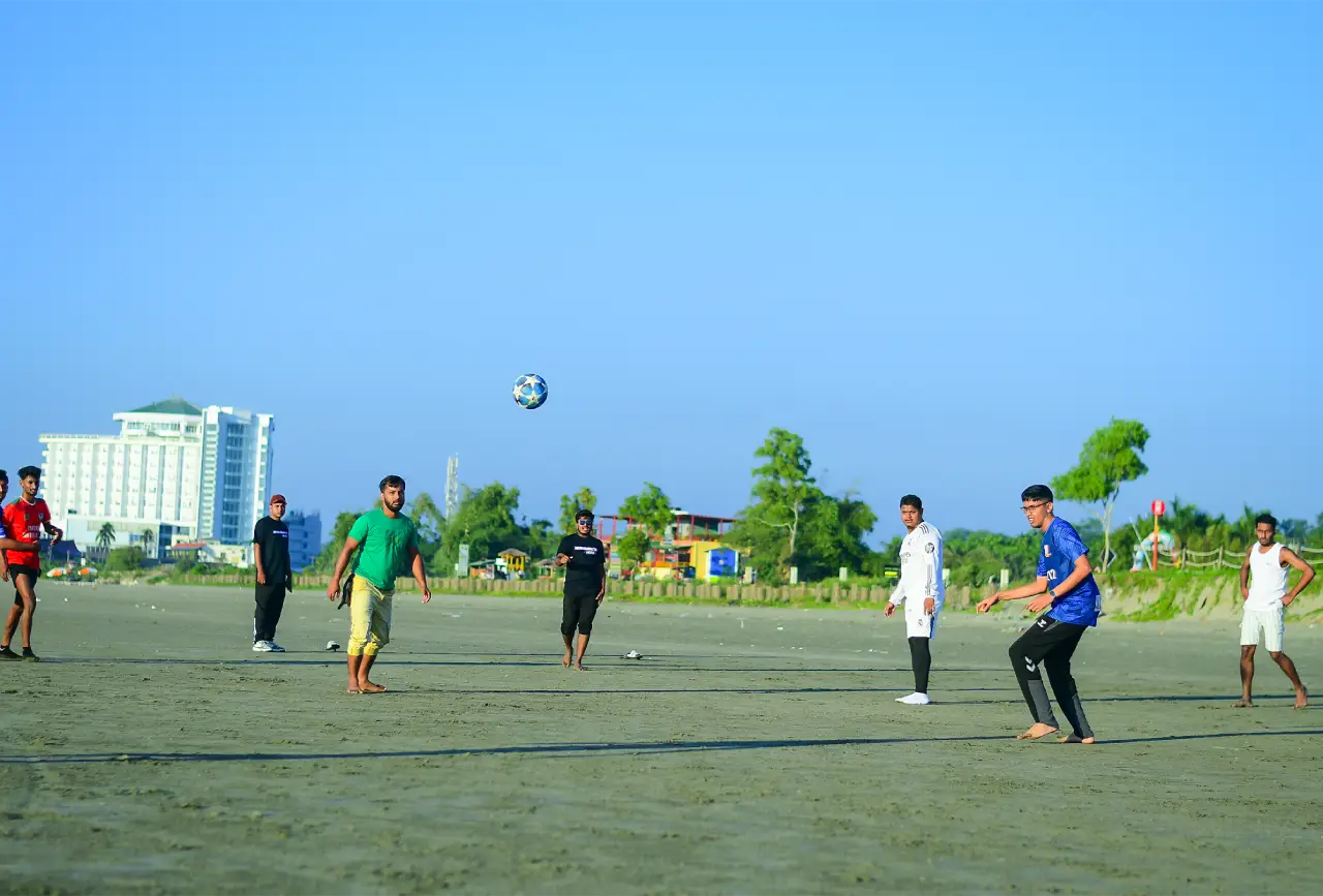 Programming Hero team members playing football on the beach